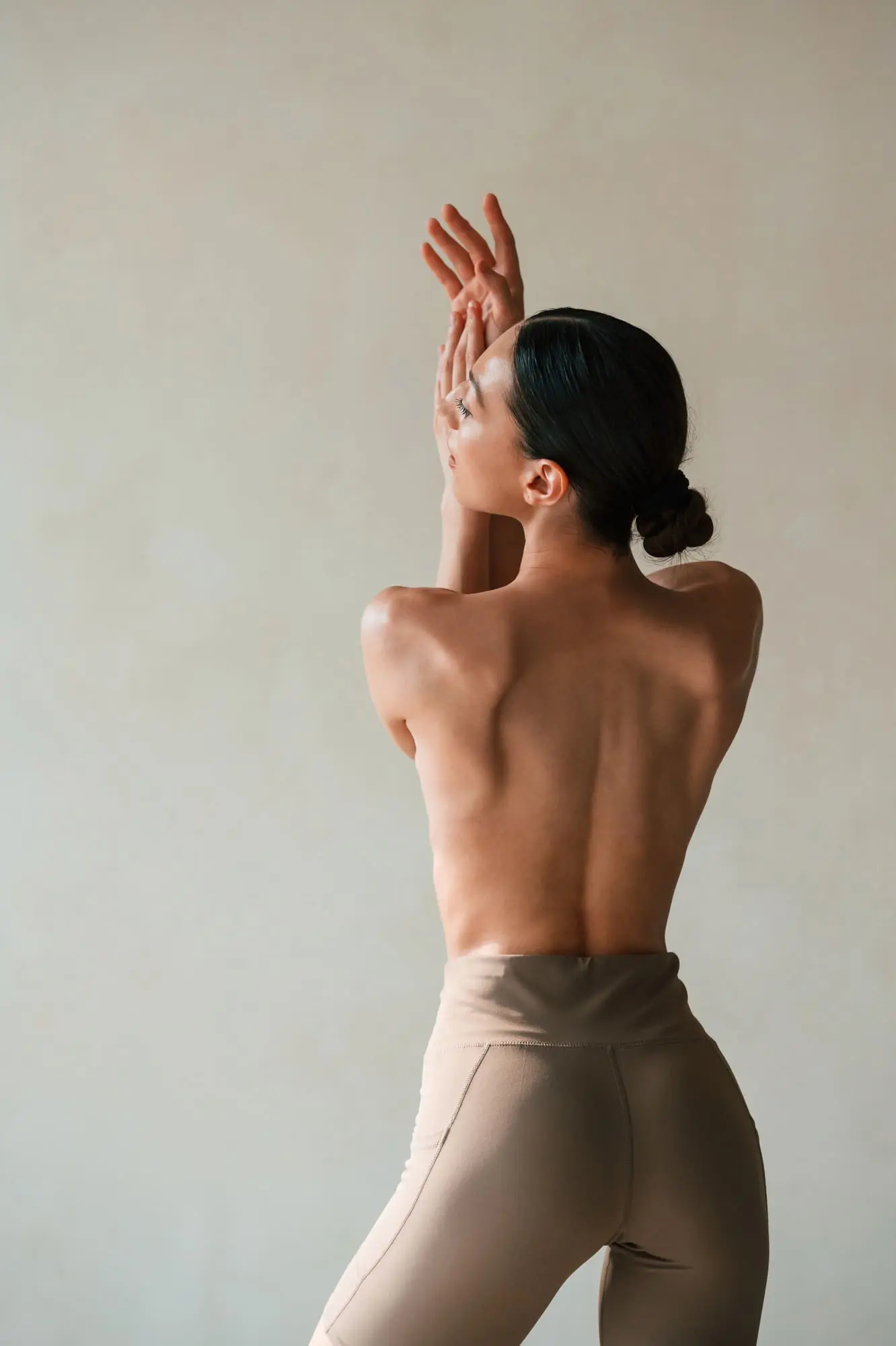 showing the spine, without bra. Young woman with slim body type is in fitness clothes in the studio