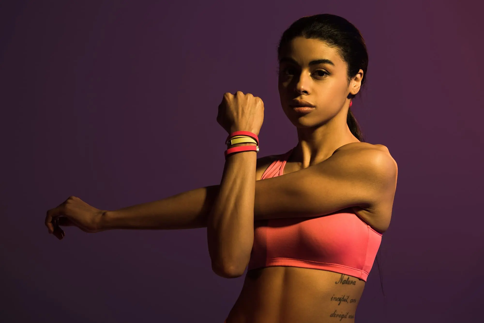 sportive young african american woman looking at camera isolated on purple