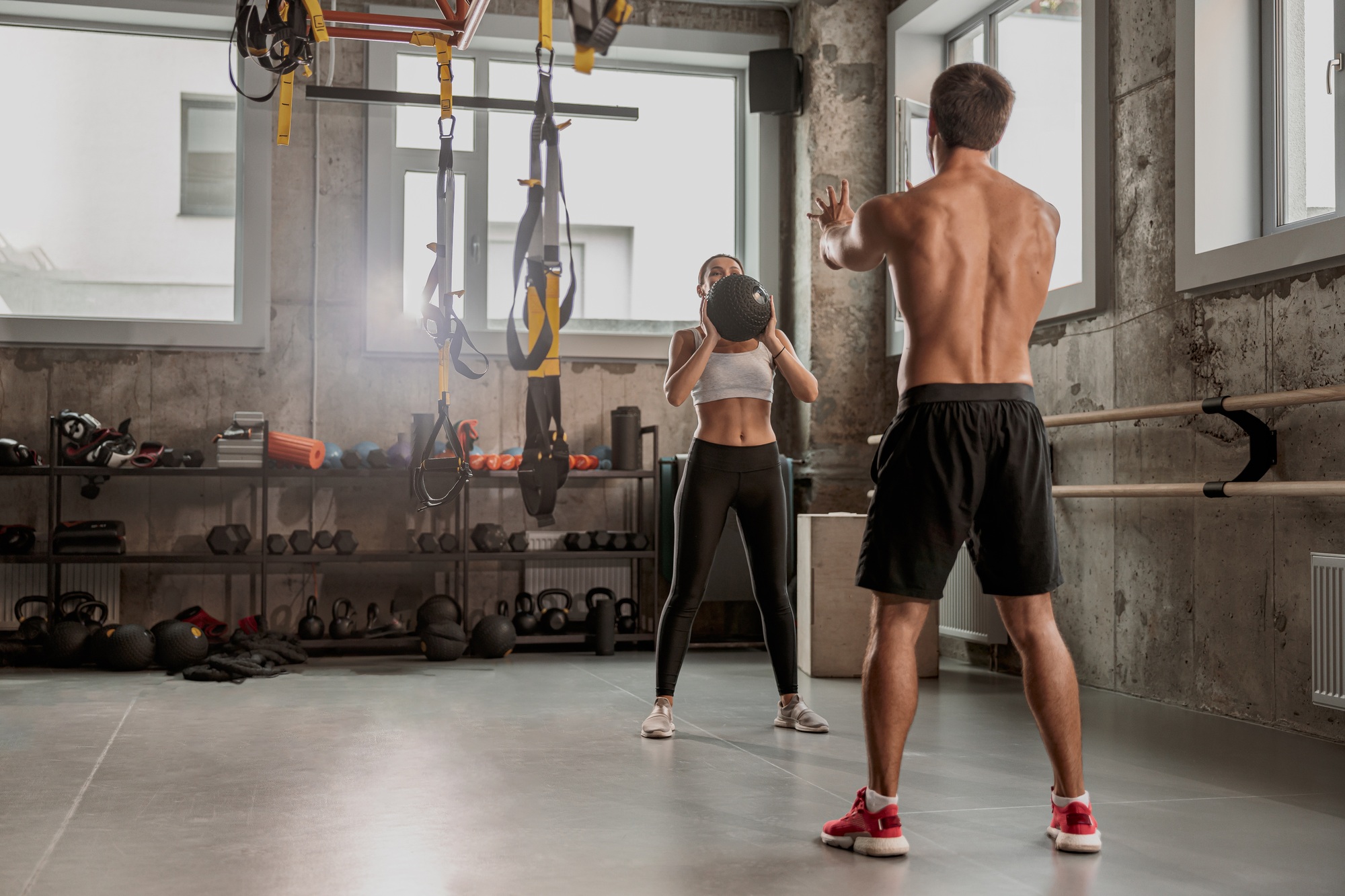 Personal coach training female client in fitness club