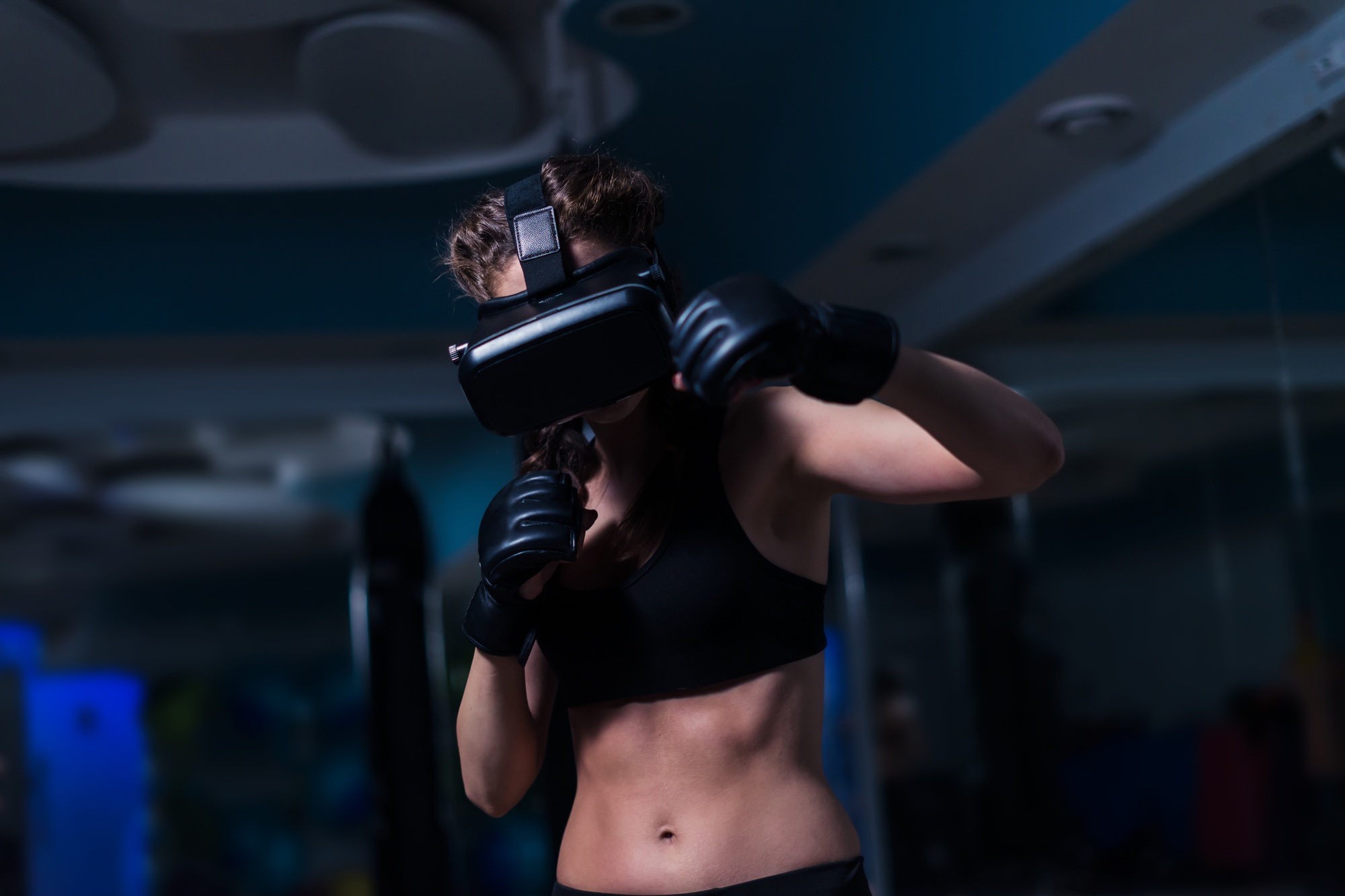 Young fighter boxer fit girl in VR glasses wearing boxing gloves